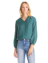 Blusa de satén color verde petróleo, con escote en V y cuello decorado con mostacillas bordadas. Presenta mangas largas con puños elásticos y ruedo también elastizado, brindando un ajuste cómodo y holgado.