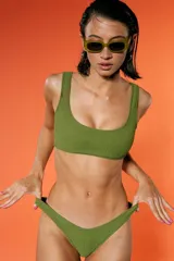 Top de bikini verde militar con textura arrugada, escote amplio y breteles fijos. Incluye bombacha vedetina con frente en V.