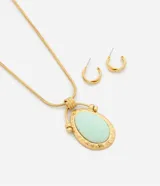 Conjunto de joyería compuesto por un collar largo con cadena tipo cola de ratón y un dije ovalado con piedra central verde agua y marco de metal martillado, acompañado por un par de aros tipo argolla pequeña.