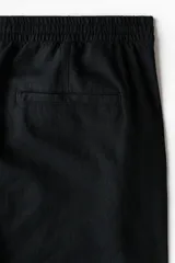 Pantalón negro de corte relajado, confeccionado en mezcla de lino y viscosa, con cintura elástica con cordón de ajuste y bolsillos laterales.