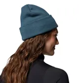 Gorro tipo beanie de punto en color azul, con diseño de doblez y etiqueta con el logo de la marca Columbia en el frente.