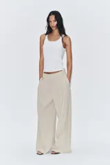 Pantalón de tiro medio color marrón, con pinzas en el delantero, perneras anchas de corte recto y trabillas para cinturón. Cuenta con bolsillos laterales y traseros, y cierre frontal con cremallera y botón.