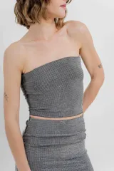 Top strapless confeccionado en tejido elástico con apliques de strass que aportan un efecto brillante tipo glitter. Silueta al cuerpo, calce cómodo y sin cierre.