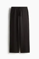 Pantalón tipo jogger de corte holgado y pierna ancha, confeccionado en felpa con interior suave. Presenta cintura elástica con cordón ajustable y bolsillos laterales discretos.