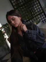 Campera de estilo camisero confeccionada en una combinación de tejidos de tweed con estampado de cuadros en tonos oscuros. Presenta mangas lisas en color marrón oscuro con parche de cuero con logo, cuello clásico, cierre frontal con botones y bolsillos frontales con solapa.