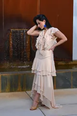 Vestido largo color beige con volados en el escote y falda escalonada.