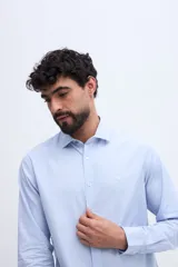 Camisa de manga larga fit semi slim color celeste, con cierre frontal de botones y cuello camisero clásico.