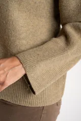 Sweater de lana de corte oversize, con cuello redondo y mangas largas con puños acanalados. Diseño de tejido liso en tono neutro.