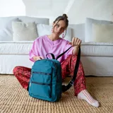 Mochila rosa de tafeta con apertura superior con cierre y tiradores metálicos, bolsillos internos, bolsillo con doble cierre metálico al frente, asas rígidas de mano y correas regulables para colgar en la espalda.