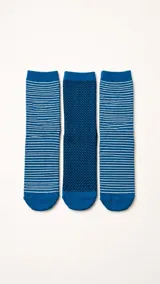 Pack de tres pares de medias de algodón en tonos azules. Dos pares presentan un diseño de rayas horizontales blancas, mientras que el par central destaca por un patrón de espiga en azul oscuro.