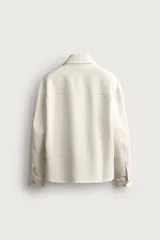 Sobrecamisa negra de corte boxy fit, confeccionada en tejido compacto. Cuenta con cuello solapa, manga larga con puños abotonados, bolsillos de parche en el pecho y cierre frontal con botones.