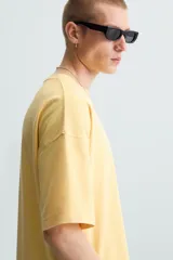 Camiseta gris de corte cuadrado y holgado, con cuello redondo y mangas cortas.