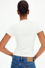 Remera de manga corta color blanco, de corte entallado con cuello redondo y bajo recto.