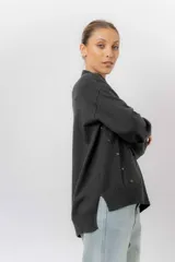 Sweater de tejido de punto color marrón, con cuello alto, corte relajado y terminaciones en rib en puños y cintura. Presenta una hilera de botones metálicos decorativos en uno de los laterales.