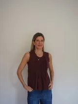 Blusa sin mangas de algodón color blanco, con delicadas tablas en el frente y terminaciones levemente desflecadas, de corte suelto y liviano.