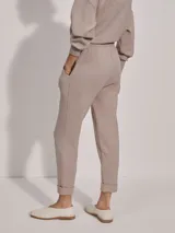 Pantalón de jogging color taupe, confeccionado en tejido DoubleSoft, con corte ajustado, pinzas delanteras y traseras, y puños enrollados en el bajo.