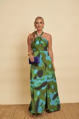 Vestido largo de satén con estampado abstracto en tonos verdes y azules, escote halter con nudo en el cuello, falda evasé y una abertura frontal pronunciada en la pierna.