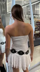 Vestido corto de encaje blanco, con diseño strapless y falda con volado en el ruedo.