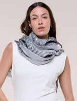 Pashmina rectangular gris con diseño jacquard, destellos de hilos metalizados y flecos en los extremos.