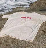 Remera oversize color crema con estampa central circular en color rojo que incluye el texto 'Chill Peel'. Presenta cuello redondo y mangas cortas con un ajuste holgado.