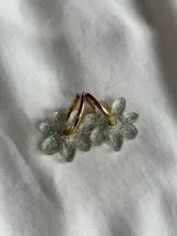 Aros de argolla metálica con dije colgante en forma de flor de acrílico color rosado.