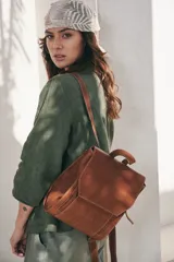 Mochila de cuero color marrón con costuras en contraste. Tiene un asa de mano y dos correas ajustables para los hombros.