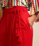 Pantalón pantalona rojo de viscosa y lino, corte amplio, con cintura con trabillas, cinturón de cuerda trenzada con abalorio y borla, y pliegues delanteros.