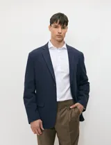 Blazer de medio forro azul marino confeccionado en mezcla de algodón y lino, con silueta estructurada, solapas de muesca, cierre frontal de dos botones y bolsillos con solapa.