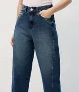 Pantalón de jean con corte new carrot, de cintura alta y estructura firme. Presenta un diseño holgado en la cadera que se estrecha hacia el bajo, con bolsillos funcionales y cierre frontal con botón y cremallera.