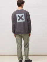 Sudadera de cuello redondo color gris oscuro, con estampado cuadrado en la espalda que contiene una X grande y texto pequeño en la parte inferior. Confeccionada en algodón orgánico de corte regular.