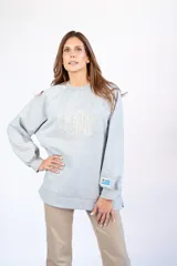 Buzo gris de calce oversize con cuello redondo y mangas largas. Presenta el logo de la marca bordado en el frente y un parche con la bandera de Uruguay en la manga izquierda.