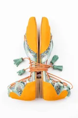Bailarinas color naranja con detalles en celeste y glitter. Cuentan con cordones de algodón con borlas de ante, cuña interna de 1,5cm y suela de cuero. Incluyen plantilla de piel y plantilla extra de lana intercambiable.