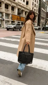 Cartera tipo tote bag negra, de diseño espacioso con solapa frontal con presilla, asas dobles y detalles en cuero sintético en las esquinas inferiores.