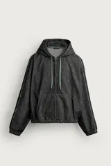 Cazadora de denim color negro con capucha ajustable con cordones, cierre frontal de cremallera, bolsillos tipo canguro y detalles de costuras en contraste en las mangas.