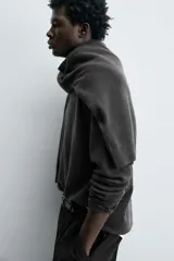 Polo de punto de manga larga con cuello solapa y cierre frontal de botones. Presenta un diseño de corte regular con aberturas laterales en el bajo.