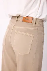 Jean de corte wide leg en color marrón chocolate, con tiro medio y cierre frontal con botón y cremallera. Presenta un diseño de cinco bolsillos y costuras visibles.