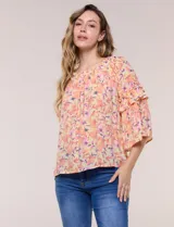 Blusa holgada de gasa estampada en tonos de amarillo, naranja y fucsia con diseño floral. Presenta escote redondo fruncido y mangas tres cuartos acampanadas con volados.