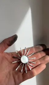 Collar con dije en forma de sol hecho a mano con centro de nácar redondo y rayos de plata. Incluye tiento de gamuza largo para usar doble o largo.