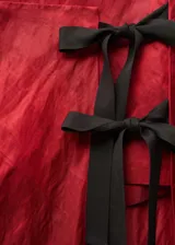 Falda midi de tiro medio con diseño recto y textura. Presenta un cierre lateral mediante lazos decorativos y una abertura pronunciada en la pierna.