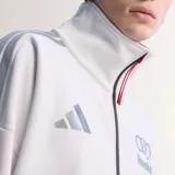 Campera adidas del equipo Audi Revolut F1 Team, de color blanco con cierre frontal negro y cuello alto. Presenta detalles de patrocinadores estampados en el pecho y las mangas, junto con las clásicas tiras de adidas en los hombros.