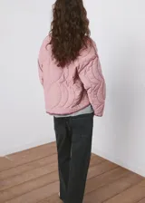 Chaqueta oversize acolchada de color rosado con diseño pespuntado en zigzag, cuello camisero, manga larga, bolsillos delanteros de parche y ribetes en contraste.