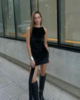 Minivestido negro de terciopelo, con cuello redondo, sin mangas y detalle de nudo en la falda.