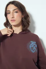 Buzo canguro color marrón con capucha y estampado de un corazón anatómico en azul en el pecho. De silueta relajada y calce cómodo.