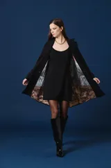 Saco largo tipo trench de color tostado, con diseño de doble botonadura, solapas clásicas y cinturón ajustable en la cintura. Presenta mangas largas con trabillas en los puños y una silueta estructurada y fluida.