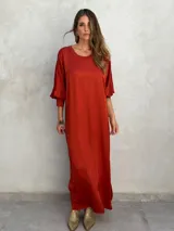 Vestido largo color ladrillo, de corte holgado, con cuello redondo y mangas 3/4 abullonadas.