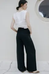 Pantalón de lino de pierna amplia y corte recto, color beige, con trabillas para cinto y cierre frontal con botón.