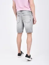 Bermuda de jean en color celeste lavado, con diseño de corte recto y detalles de roturas desgastadas en la parte frontal.