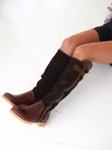 Botas altas de cuero marrón combinadas con gamuza blanca con estampado de vaca, forradas en cuero y con cierre de bronce.