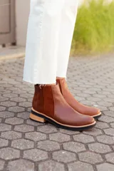 Botas tipo Chelsea de cuero, con diseño de paneles combinados en texturas lisas, gamuzadas y con relieve tipo reptil en el talón. Presentan una suela plana con taco bajo de madera y base de goma negra.