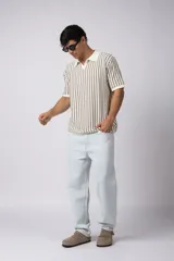 Chomba de tejido de punto con diseño de rayas verticales en tonos beige y marrón, cuello polo y mangas cortas con terminación acanalada.